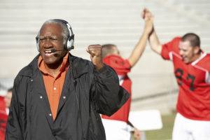 Football coach shouting and pumping fist with football players i